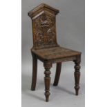 A late Victorian carved oak hall chair, the shaped back carved with a Green Man mask, the solid seat