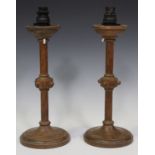 A pair of early 20th century Arts and Crafts style oak table lamps, the stems with beaded knops,