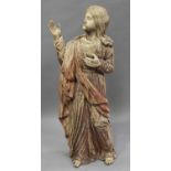 An Eastern carved wooden figure of Jesus Christ wearing long robes and holding one hand aloft,