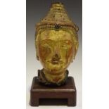 A South-east Asian gilded and carved wooden head of a buddha, inset with coloured glass, height