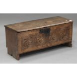A 17th century elm six plank coffer, the hinged lid above a carved panel front, on shaped ends,