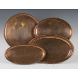 A group of four Arts and Crafts copper trays by Hugh Wallace, one engraved with a ship, length 43cm,