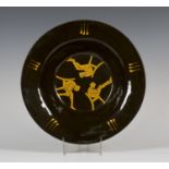 A Prue Cooper studio pottery slipware dish of flared circular form, covered in a dark brown glaze,