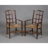 A pair of early 20th century Arts and Crafts Cotswold School oak elbow chairs, the shaped lattice
