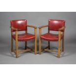 A pair of early 20th century Arts and Crafts oak framed elbow chairs, in the manner of Heals, the