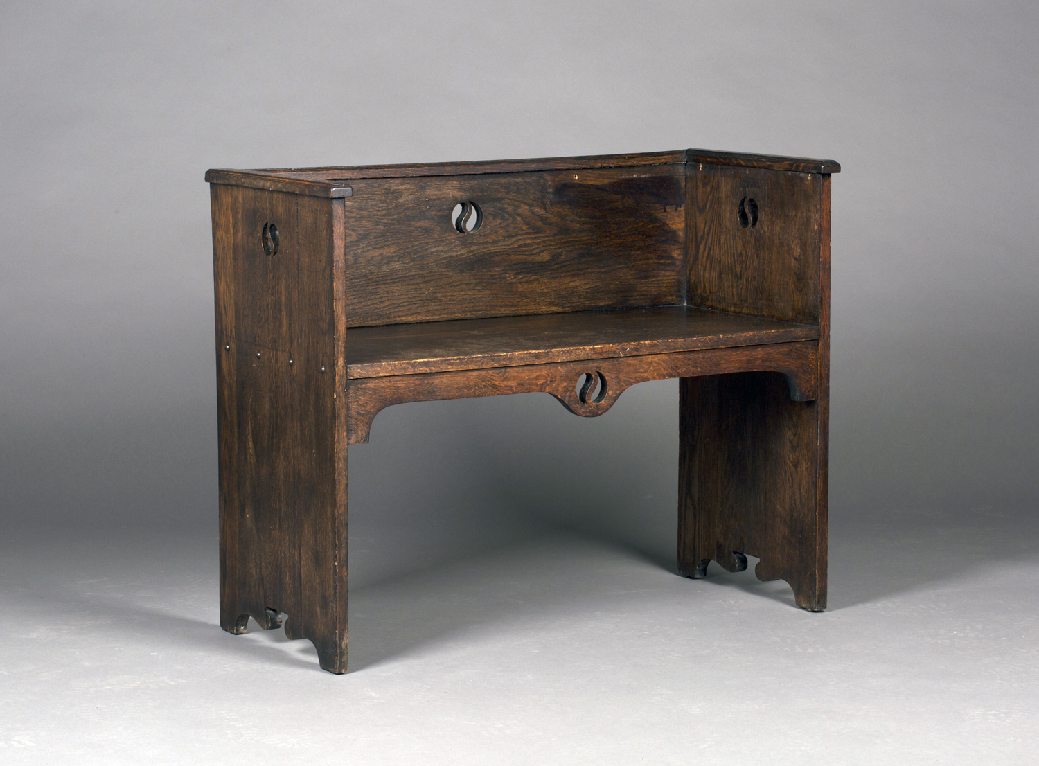 An early 20th century Arts and Crafts style stained oak hall bench, possibly by Liberty & Co, the