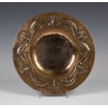 An early 20th century Arts and Crafts copper circular dish, the raised rim finely worked with a band