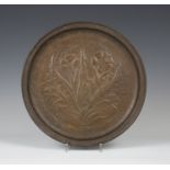 An early 20th century Arts and Crafts copper circular dish, worked with an overall stylized