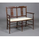 An Edwardian Arts and Crafts stained beech salon settee, in the manner of William Birch, raised on