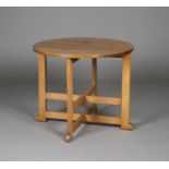 An early 20th century oak circular occasional table, in the manner of Heals, raised on block