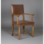 A mid-20th century Arts and Crafts style oak framed elbow chair, manufactured for the War Department