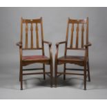 A pair of Edwardian Arts and Crafts Glasgow School oak framed elbow chairs, possibly designed by E.
