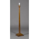 An early 20th century Arts and Crafts oak lamp standard, the tapering stem raised on a shaped square