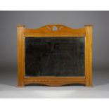 An Edwardian Arts and Crafts oak overmantel mirror, in the manner of Liberty & Co, the shaped top