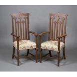 A pair of Edwardian Arts and Crafts oak framed elbow chairs by Allen & Appleyard of Liverpool, the