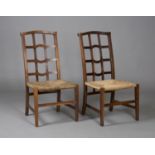A pair of early 20th century Arts and Crafts Cotswold School oak side chairs, the shaped lattice