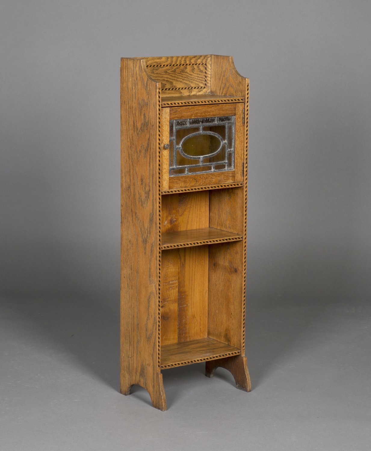 An early 20th century Arts and Crafts oak narrow bookcase, in the manner of Liberty & Co, fitted