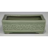 A Chinese celadon glazed rectangular planter, early 20th century, the sides moulded in relief with