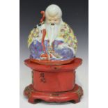 A Chinese famille rose porcelain figure of Shoulau, early 20th century, modelled seated wearing a