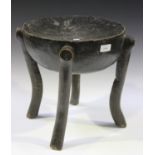An African carved hardwood stool, the dished circular seat raised on four integral carved legs,