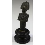An Egyptian style patinated metal figure of a pharaoh with elaborate headdress and crossed arms,