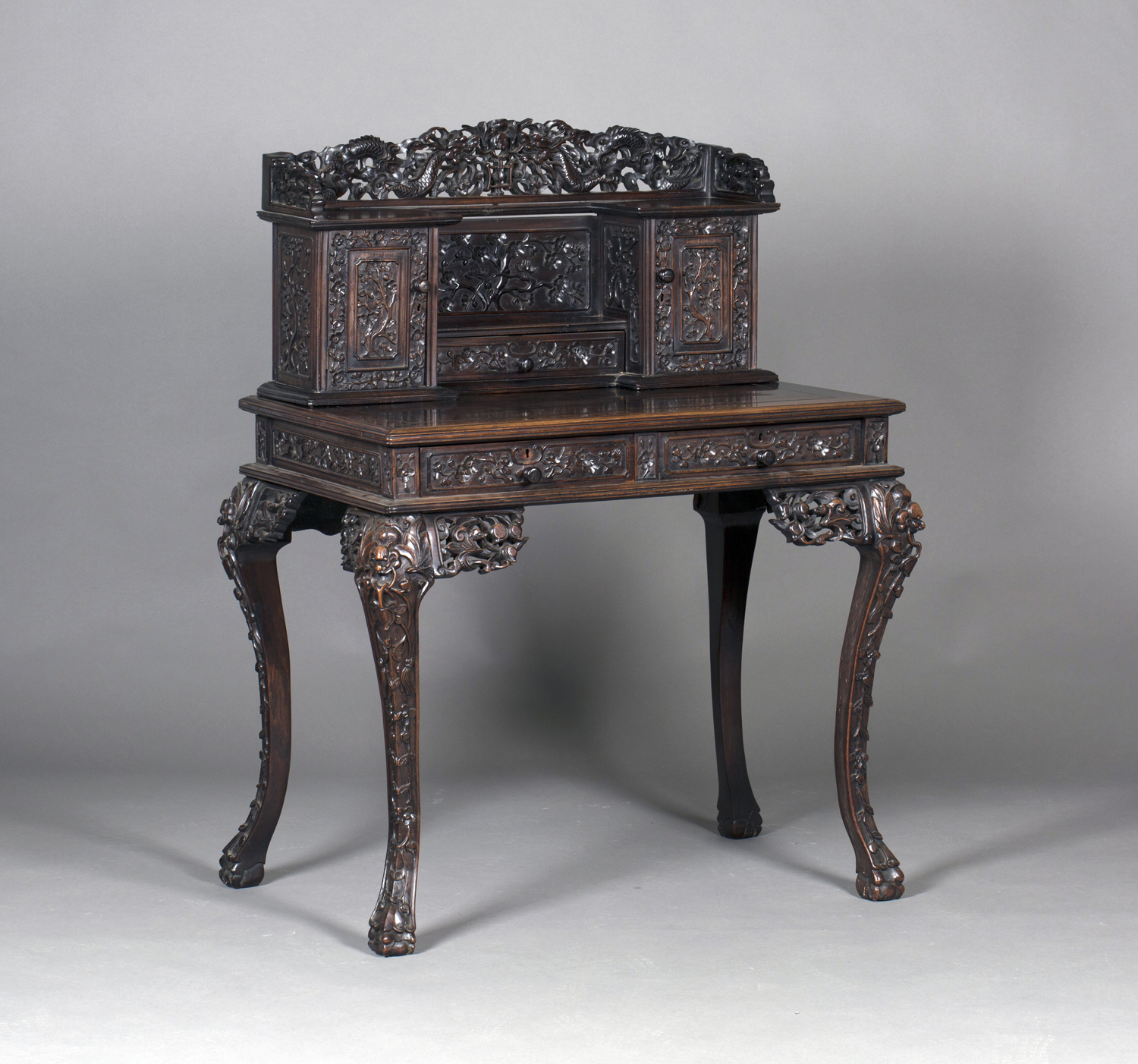 A Chinese hardwood writing desk with carved blossoming prunus decoration, late 19th century, the