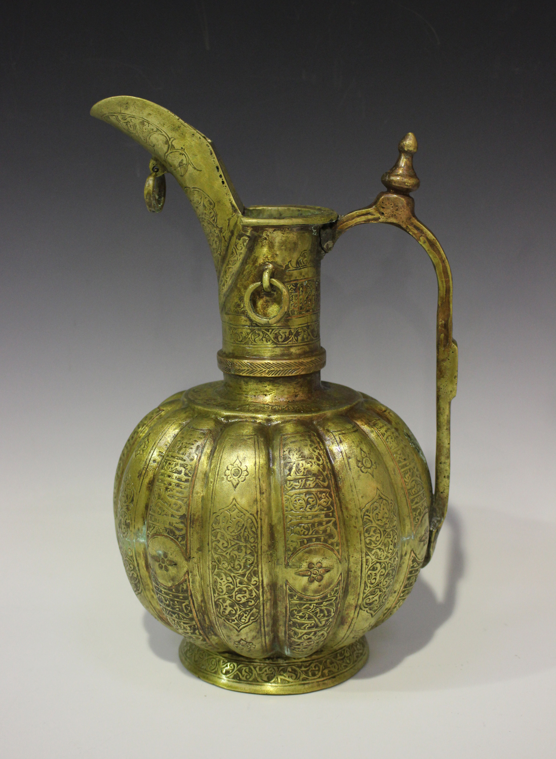 A Khorasan brass ewer, the lobed body and flared neck engraved with foliate and script panels within