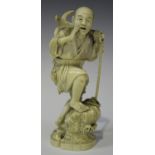 A Japanese carved ivory okimono figure of a fisherman, Meiji period, modelled standing on a rocky