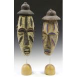 Two Igbo carved and painted masks, Nigeria, both mounted on domed oak bases, heights of masks 49cm