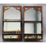 A pair of Victorian walnut mirror back two-tier hanging wall shelves with wrought metal supports and