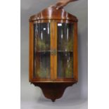 An Edwardian mahogany bowfront corner display cabinet with arched pediment and chequer stringing,