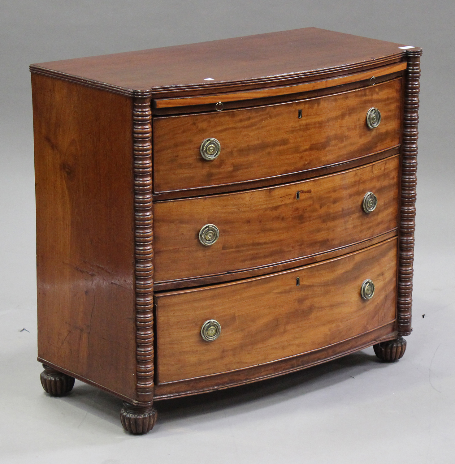 A late George III mahogany bowfront chest with brushing slide above three graduated long drawers,