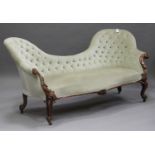 A late Victorian mahogany salon settee, upholstered in buttoned green velour, carved with acanthus