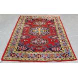 A Persian rug, mid/late 20th century, the red field with a hooked blue medallion, within a pale blue