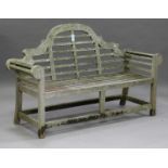 A late 20th century teak garden bench, after a design by Sir Edwin Lutyens, the arched and slatted