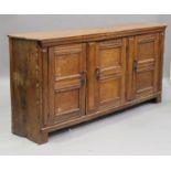 An 18th century German oak enfilade side cabinet, fitted with three panelled doors, on bracket feet,