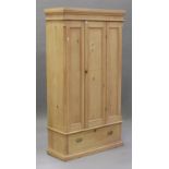 A 19th century stripped pine wardrobe, enclosed by a single door above a drawer, on a plinth base,