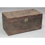 A 20th century Chinese camphor trunk, the hinged lid and sides carved with figures in landscapes,