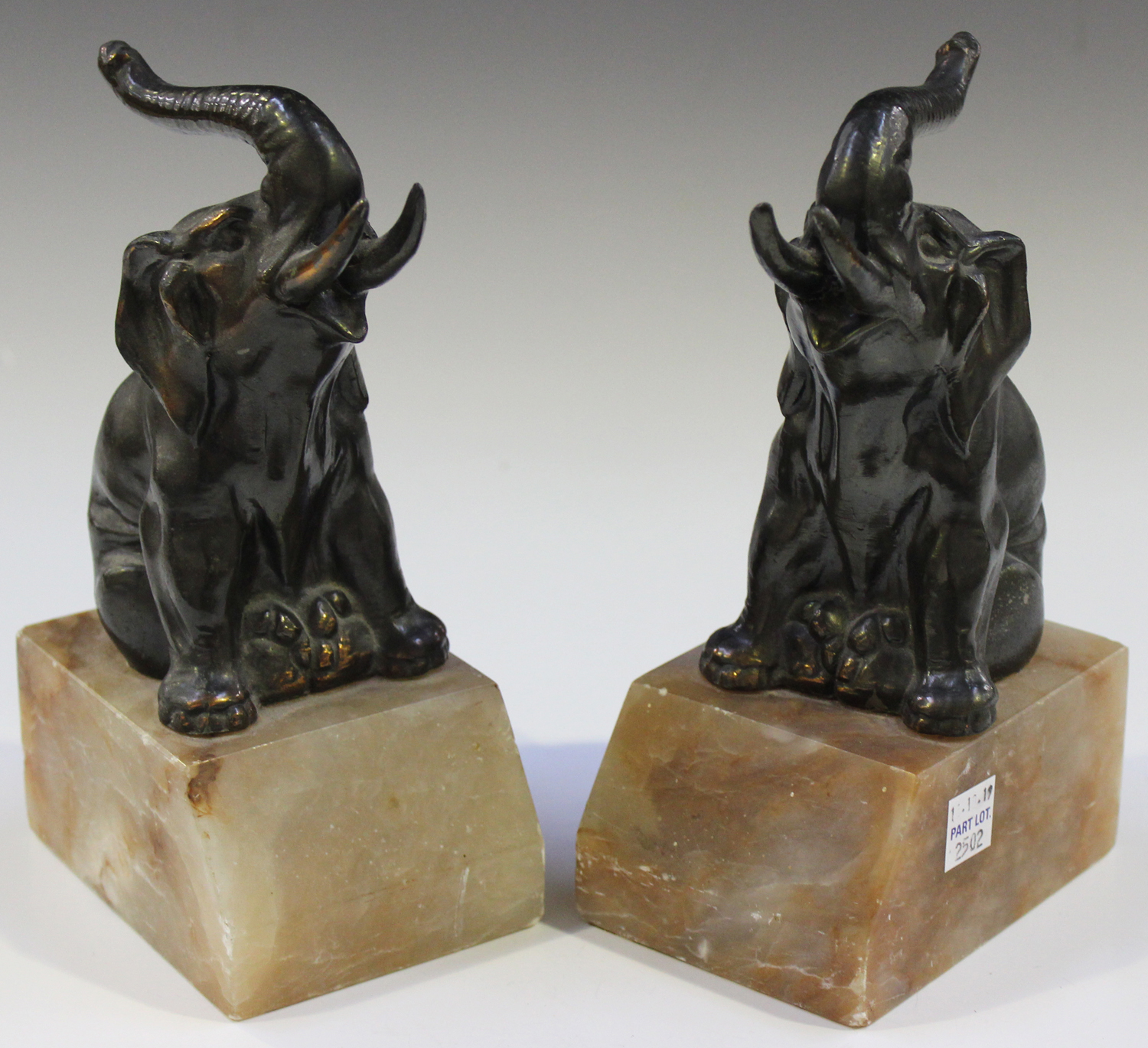 A pair of French Art Deco anodized cast spelter and pink toned onyx bookends, each modelled in the