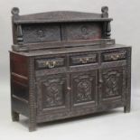 An 18th century oak dresser, later profusely carved with masks and scrolls, fitted with three