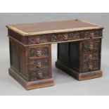A Victorian oak twin pedestal desk, profusely carved with foliate masks, fitted with an