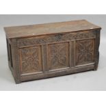 A 17th century oak coffer with later carved decoration, the hinged lid above a triple panel front,