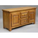 A modern oak side cabinet, the rectangular top above two drawers flanked by cupboards, on block