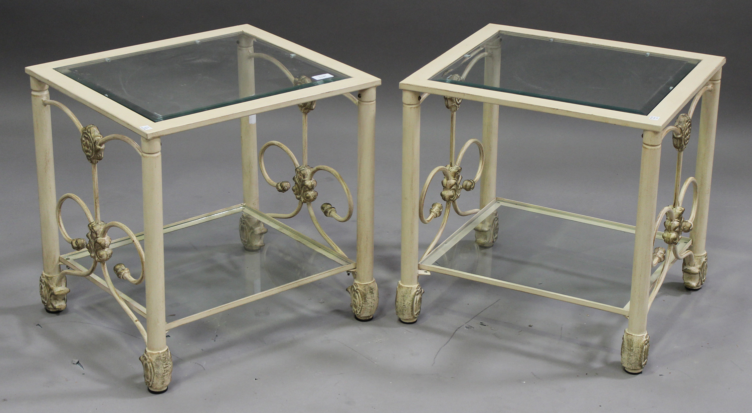A pair of modern cream and gilt painted metal occasional tables with glass tops and undertiers,