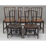 A harlequin set of five George III elm and fruitwood comb back dining chairs, each with a solid