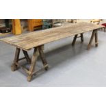A large early 20th century French pine trestle table, the rectangular plank top raised on block