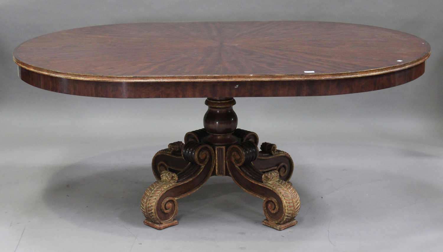 A 20th century American figured mahogany and gilt painted dining table, the rounded top raised on