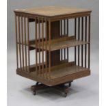 An Edwardian oak revolving bookcase, the slatted sides raised on an iron frame base with castors,