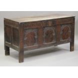 A large mid-17th century carved oak coffer with triple arched panel front, on stile supports, height