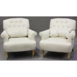 A pair of modern button back armchairs, upholstered in cream fabric, raised on turned legs and brass